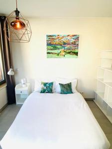 卢森堡Large Studio in Center with Terrace-Cosy的卧室配有白色的床和墙上的绘画作品