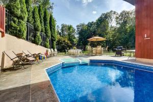 伍德伯里Spacious Woodbury Home with Pool and Hot Tub!的庭院内的游泳池配有椅子和遮阳伞