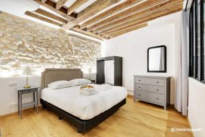 巴黎Amazing Apartment 2BR6P - St Lazare South Pigalle的一间卧室设有一张床和石墙