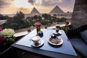 开罗PANORAMA view pyramids的一张桌子,上面放着两杯咖啡和一盘食物