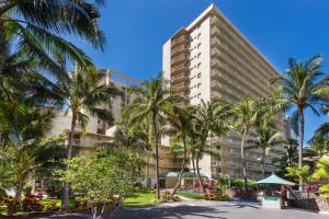 檀香山威基基海滩万怡酒店 的一座高大的建筑,前面有棕榈树