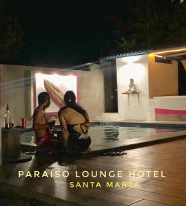 圣玛尔塔Paraiso Lounge的两个男人晚上坐在游泳池旁边
