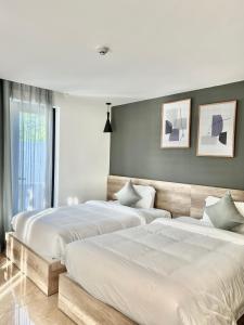 芽庄La Sera Suites Nha Trang的卧室内的两张床,配有白色床单
