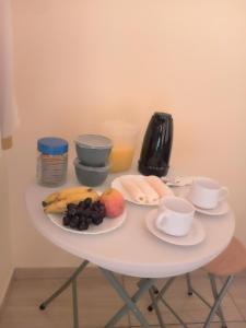 圣阿马鲁Hospedaria genivaldo的一张带一盘水果和咖啡杯的白色桌子
