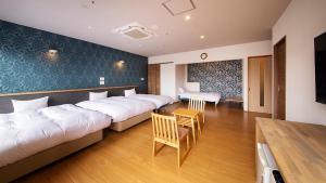 萩市リゾートホテル美萩的酒店客房设有两张床和一张桌子。