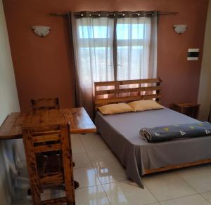 Rodrigues IslandPanoramic Paradise的一间卧室配有一张床、一张桌子和一个窗户。