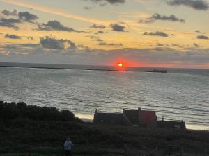 滨海布洛涅SERENITY VIEW Villa face mer aux magnifiques couchers de soleil的站在海滩上观看日落的人