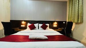 勒克瑙CORAL TREE INN的一间卧室配有一张带红色和白色枕头的大床