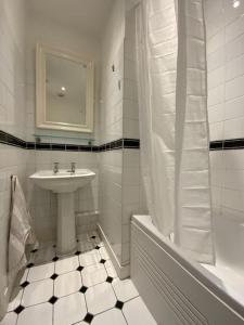 法纳姆Ipsley Lodge Apartment Surrey Hills的白色的浴室设有水槽和浴缸。