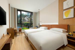 淳安voco千岛湖阳光大酒店的卧室配有一张白色大床和电视。