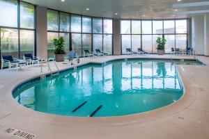 伍德森特瑞斯圣路易斯机场希尔顿酒店的一座大型游泳池,位于一座带窗户的建筑内