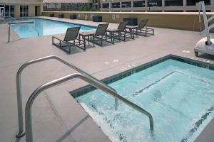 莫德斯托莫德斯托希尔顿逸林酒店的一个带椅子和热水浴缸的大型游泳池