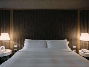 利马Manto Hotel Lima - MGallery的一间卧室配有一张带两盏灯的大型白色床。