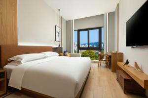 淳安voco千岛湖阳光大酒店的卧室配有白色的床和平面电视。
