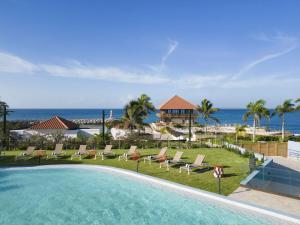 拉罗马纳Hilton Garden Inn La Romana的一个带椅子的游泳池,背景是大海