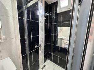 伊斯坦布尔STONE HOME Hostel的黑色瓷砖浴室设有淋浴和卫生间