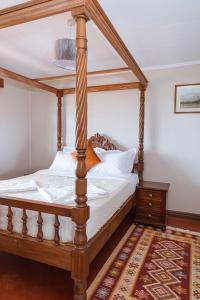 安博塞利Wild Amboseli Ndovu Cottage.的一张木制四柱床,位于一间铺有地毯的房间