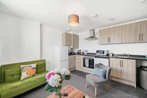 斯劳Heathrow Haven: Stylish Apartments in the Heart of Slough的一间带绿色沙发的客厅和一间厨房