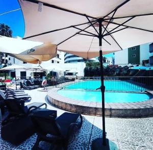 圣保罗湾城圣安东公寓式酒店的游泳池旁的游泳池配有椅子和遮阳伞