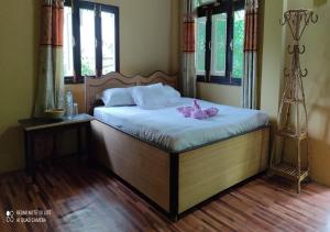 BhurkīāTiger Land Homestay的一间卧室配有一张铺有白色床单和粉红色鲜花的床。
