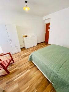 新松奇Komfortowy pokój dla dwojga z balkonem Marcinkowicka的一间卧室设有绿色的床,铺有木地板