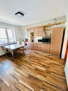 新松奇Komfortowy pokój dla dwojga z balkonem Marcinkowicka的厨房铺有木地板,配有桌子。