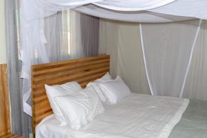 波特尔堡Dutchess Hotel and Restaurant的白色的床、白色枕头和天蓬