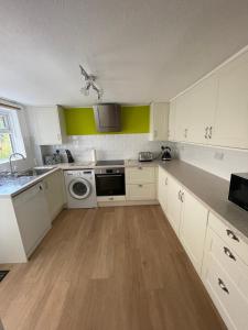 伊斯特布恩Garden flat in 'Little Chelsea'的厨房配有白色橱柜、洗衣机和烘干机