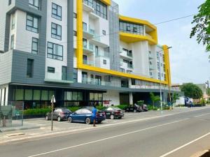 阿克拉Labone Luxury Condo and Apartment in Accra - FiveHills homes的停车场内停放汽车的大型建筑