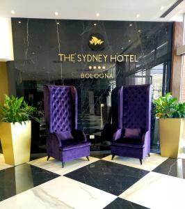 博洛尼亚The Sydney Hotel的酒店大堂的两把紫色椅子