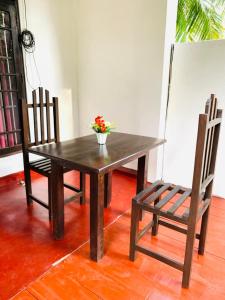 达瓦拉维孔雀别墅度假村的一张带花瓶和椅子的木桌