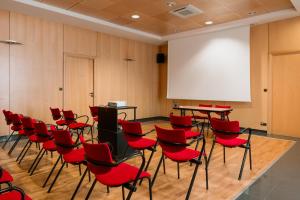普瓦捷贝斯韦斯特普瓦捷酒店的一间设有红色椅子和白色屏幕的讲座室