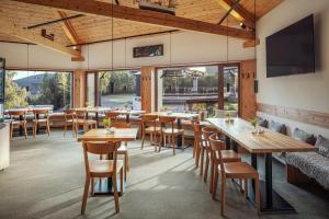 哈拉霍夫Ski & Spa hotel BELLEVUE的餐厅设有木桌、椅子和窗户。