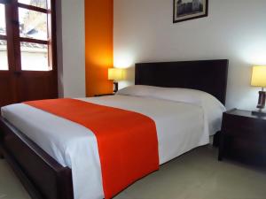 波帕扬Hotel Arcadia Colonial的一间卧室配有一张大床,铺有红白毯子