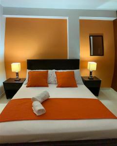 波帕扬Hotel Arcadia Colonial的一间卧室配有一张带橙色枕头的大床和两盏灯。