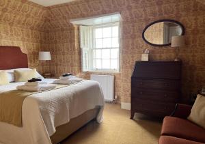 奥本The Manor House Hotel的一间卧室配有床、镜子和梳妆台