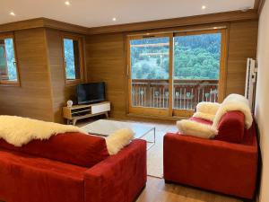 美贝尔Newly renovated 7-9pers Luxury Chalet in Meribel Centre 85m2 3BR 3BA with stunning Mountain View的客厅配有2张红色沙发和1台电视