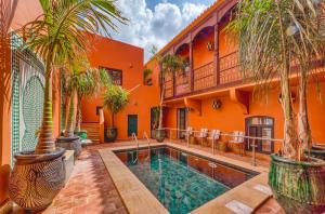 西尔韦斯Casa Riad Yasmin的一座带游泳池和棕榈树的橙色房子