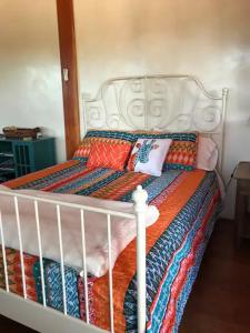 圣达菲Casita Luna的一张白色的床,上面有色彩缤纷的毯子和枕头