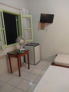 圣洛伦索Pousada Samambaia SL的小房间设有一张床和一张带风扇的桌子
