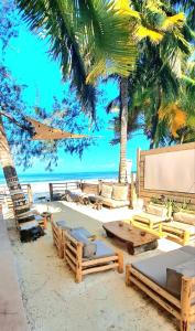 吉汶瓦Boho Boutique Villa - Adults Only的棕榈树海滩,沙滩上摆放着桌椅
