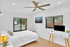 好莱坞Tropical Oasis with pool 10 mins airport & 5 mins Beach的一间卧室配有一张带书桌的床和吊扇。