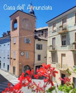 Chiusa di PesioCasa dell’Annunziata的一座建筑,前方有一座钟楼,上面有红花
