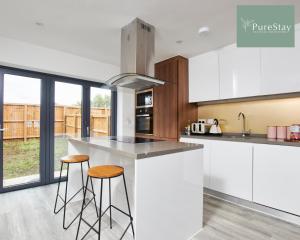 曼彻斯特Perfect for Business Stays in Manchester - 5 Bedroom House By PureStay Short Lets & Serviced Accommodation的厨房配有白色橱柜和酒吧凳子