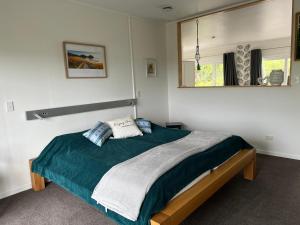 图图卡卡Tutukaka Sunrise的一间卧室配有一张带绿毯和镜子的床
