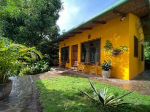 La LagunaCasa Única - Room with breakfast or Cabins with kitchen的院子里的黄色房子,配有桌椅
