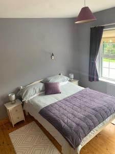 蒂珀雷里Garrenmore Lodge B&B的一间卧室配有一张带紫色棉被的床和窗户。