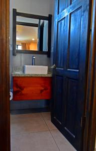 蓬塔雷纳斯Hotel Cabinas Midey的一间带水槽和蓝色门的浴室