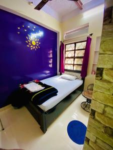 瓦拉纳西玛丽戈尔德旅馆的一间卧室配有一张紫色墙壁的床