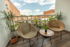 麦德林La Martina Hotel Boutique的种植了植物的阳台,配有三把椅子和一张桌子